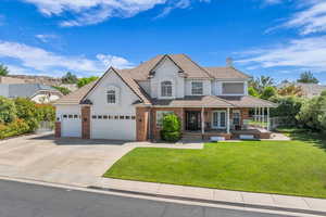 View of front of home featuring covered porch, stucco siding, a chimney, and a front lawn