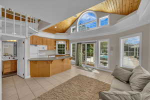Kitchen featuring white appliances, open floor plan, a breakfast bar, and wood ceiling