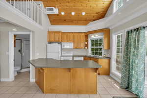 Kitchen featuring white appliances, light tile patterned flooring, dark countertops, and wooden ceiling