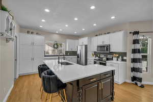 Kitchen featuring stainless steel appliances, baseboards, white cabinetry, and a sink