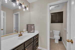 Bathroom with tile patterned flooring, vanity, toilet, baseboards, and visible vents