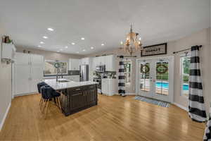 Kitchen with baseboards, light wood-type flooring, a chandelier, a sink, and appliances with stainless steel finishes
