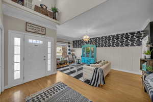Foyer entrance with crown molding, wainscoting, light wood finished floors, a textured ceiling, and a chandelier