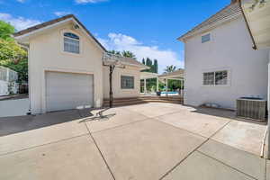 Exterior space with concrete driveway, a garage, cooling unit, and stucco siding