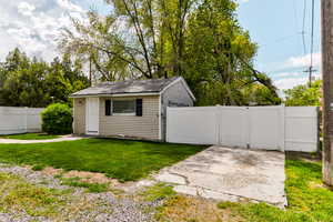 View of outdoor structure with a gate, fence, and an outbuilding