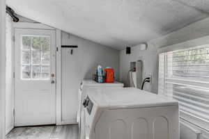 Washroom with independent washer and dryer, a textured ceiling, laundry area, and light wood finished floors