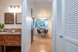 Corridor with a sink, baseboards, light wood-style flooring, and a chandelier