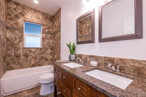 Full bathroom with double vanity, a sink, washtub / shower combination, and toilet