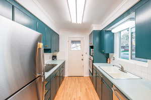 Kitchen with a sink, light wood-style flooring, appliances with stainless steel finishes, and tasteful backsplash