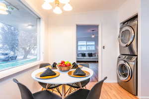 Dining room featuring light wood-style floors, an inviting chandelier, stacked washer and clothes dryer, and crown molding
