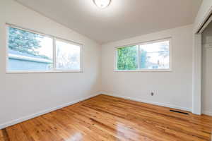 Unfurnished bedroom featuring baseboards, vaulted ceiling, light wood finished floors, and visible vents