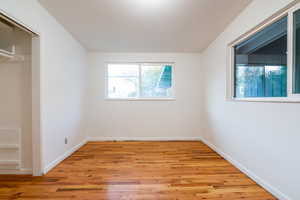 Unfurnished bedroom featuring light wood-type flooring, baseboards, and multiple windows