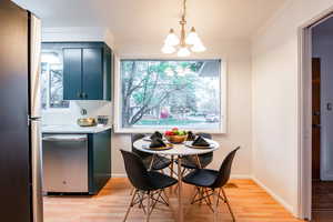 Dining room with an inviting chandelier, crown molding, a wealth of natural light, and light wood-type flooring