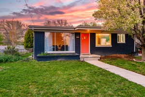 View of front of house featuring fence, a yard, and brick siding