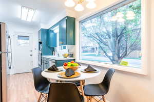 Dining area with plenty of natural light, ornamental molding, light wood-style floors, and a notable chandelier