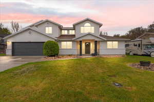 Traditional-style home with roof with shingles, a garage, stucco siding, a front yard, and driveway