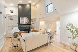 Living room with visible vents, baseboards, light wood-type flooring, recessed lighting, and built in shelves
