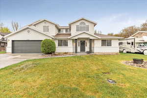 Traditional-style home featuring roof with shingles, a front lawn, a garage, stucco siding, and concrete driveway