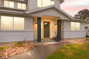 Exterior entry at dusk featuring brick siding and stucco siding