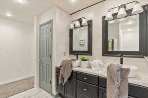Bathroom featuring double vanity, marble finish floor, baseboards, a textured ceiling, and a sink