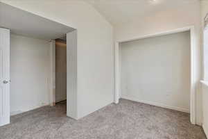 Carpeted spare room featuring lofted ceiling