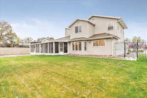 Back of property featuring a chimney, a lawn, a gate, a sunroom, and fence