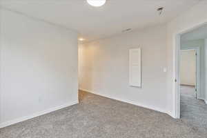 Carpeted spare room featuring visible vents and baseboards