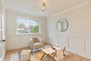 Living area featuring a wainscoted wall, light wood finished floors, and a decorative wall