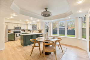 Interior space with crown molding, light wood-style floors, a tray ceiling, and a textured ceiling