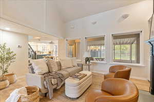Living room featuring stairway, high vaulted ceiling, baseboards, and light wood finished floors