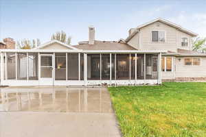 Back of property with a sunroom, a lawn, roof with shingles, and a chimney