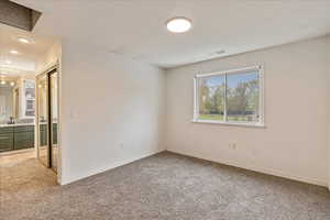 Unfurnished bedroom featuring a sink, baseboards, light carpet, and connected bathroom