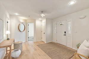 Entrance foyer with baseboards, a textured ceiling, light wood-style flooring, and recessed lighting