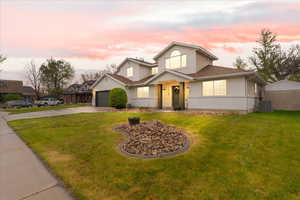 Traditional home with a garage, driveway, a front lawn, and stucco siding