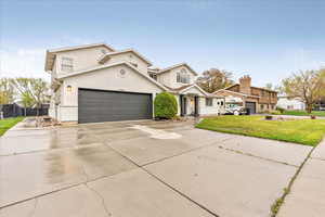 Traditional-style house with a front lawn, fence, stucco siding, concrete driveway, and an attached garage