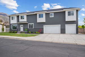 View of front of home with a garage, fence, a mountain view, a front lawn, and concrete driveway