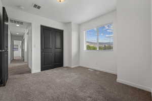 Unfurnished bedroom featuring a closet, baseboards, carpet flooring, and visible vents