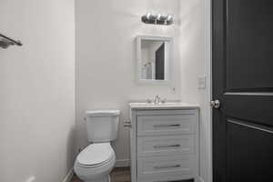 Half bathroom with toilet, baseboards, and vanity