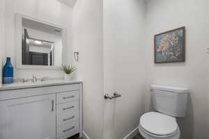 Half bathroom featuring visible vents, toilet, and vanity