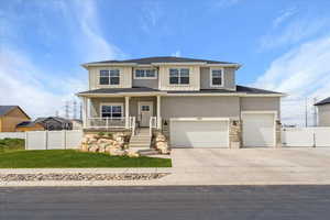 View of front of home featuring fence, an attached garage, a porch, and stone siding