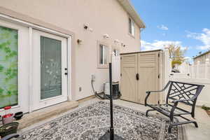 View of patio featuring central AC, fence, an outbuilding, and a shed