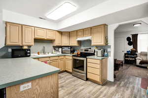 Kitchen featuring black microwave, a sink, light brown cabinets, under cabinet range hood, and stainless steel electric stove