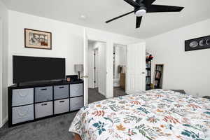 Bedroom with baseboards, ensuite bathroom, a ceiling fan, and dark carpet