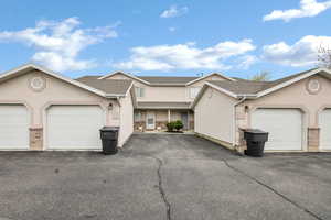 View of property featuring stucco siding and community garages