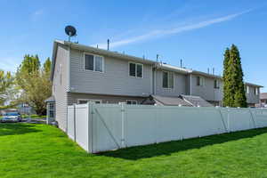 Back of property with a lawn, fence, and a gate