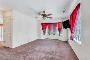 Carpeted empty room featuring baseboards, ceiling fan, and visible vents
