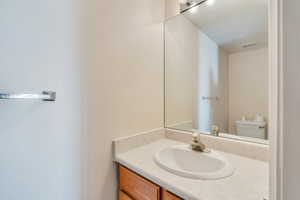 Half bathroom with toilet, visible vents, and vanity