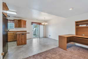 Kitchen with brown cabinets, a notable chandelier, a sink, a textured ceiling, and decorative light fixtures