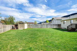 View of yard with a fenced backyard, a storage unit, and an outbuilding