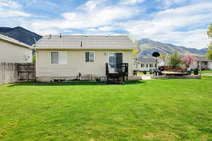 Back of house with a lawn, fence, and a mountain view